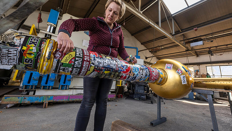 Andrea Würzinger entfernt Aufkleber vom Zugspitz-Gipfelkreuz. Bis zum 28. November, dem Saisonstart, wird sie es in Eschenlohe restaurieren.