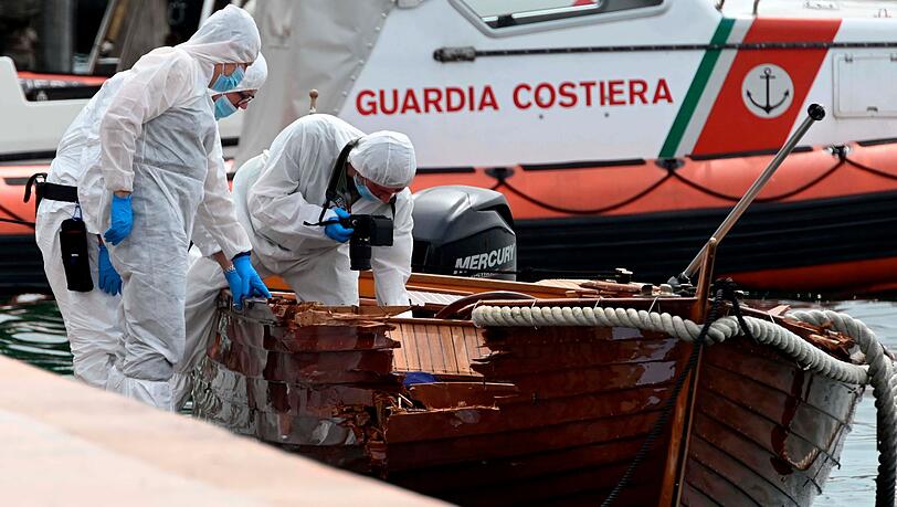 Forensiker begutachten im Hafen den Schaden an einem Holzboot.