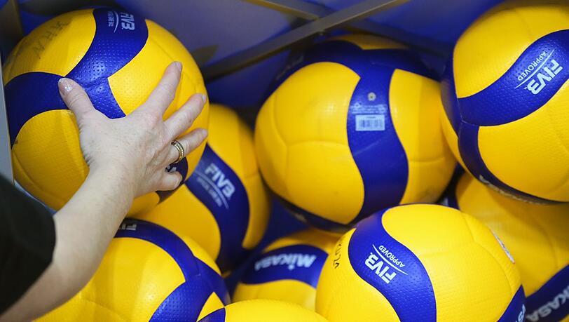 Die Hand einer Frau hält einen Volleyball.