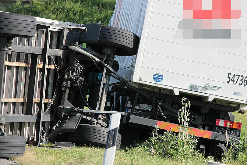 Vermutlich weil er zu schnell auf die Autobahn fährt, kommt ein Laster in der Kurve von der Fahrbahn ab und fährt in die Leitplanke. Sein Hänger kippt um.
