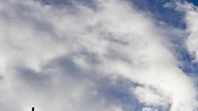 Das Kreuz einer Kirche ist vor bewölktem Himmel zu sehen. Foto: Nicolas Armer/Archivbild