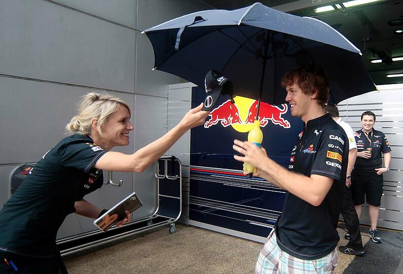 Kappe und Schirm gegen den Monsun: Pressesprecherin Britta Röske und Weltmeister Sebastian Vettel.