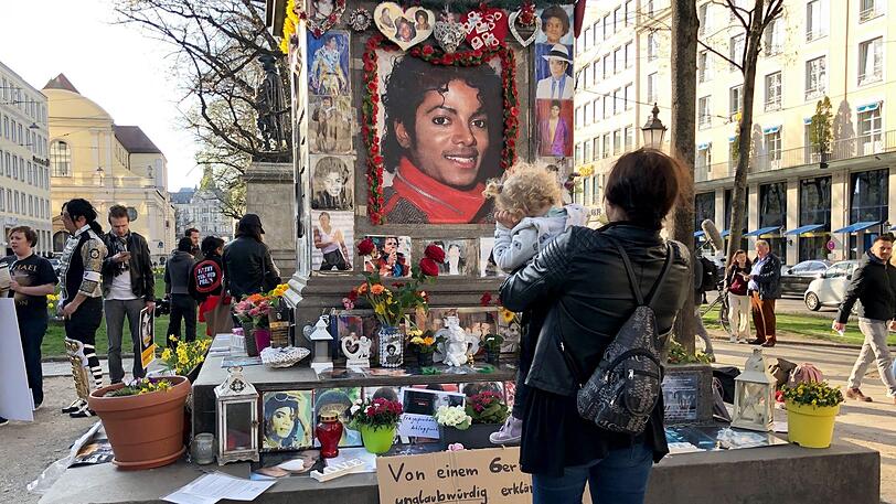 Eine Frau steht vor dem Denkmal für Orlando-di-Lasso, einem Komponisten und Kapellmeister der Renaissance, das vor dem Bayerischen Hof zum Michael Jackson Denkmal umfunktioniert wurde und betrachtet die Gedenkbekundungen.