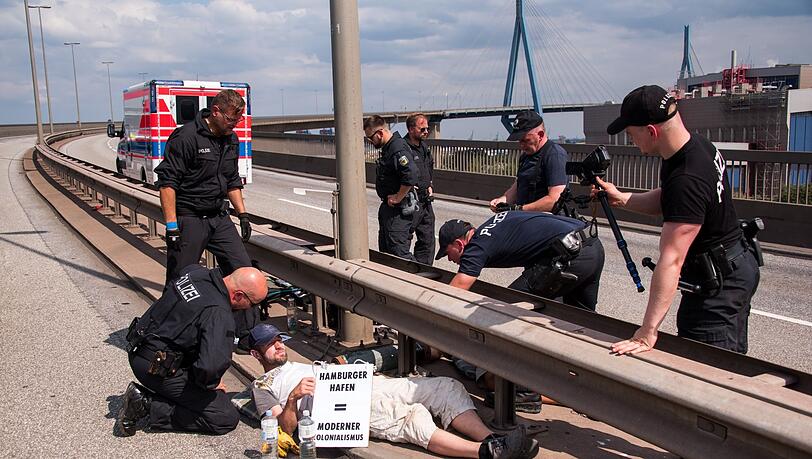 Polizisten versuchen auf der Köhlbrandbrücke zwei mit einem Eisenrohr miteinander verbundene Klimaaktivisten zu lösen.
