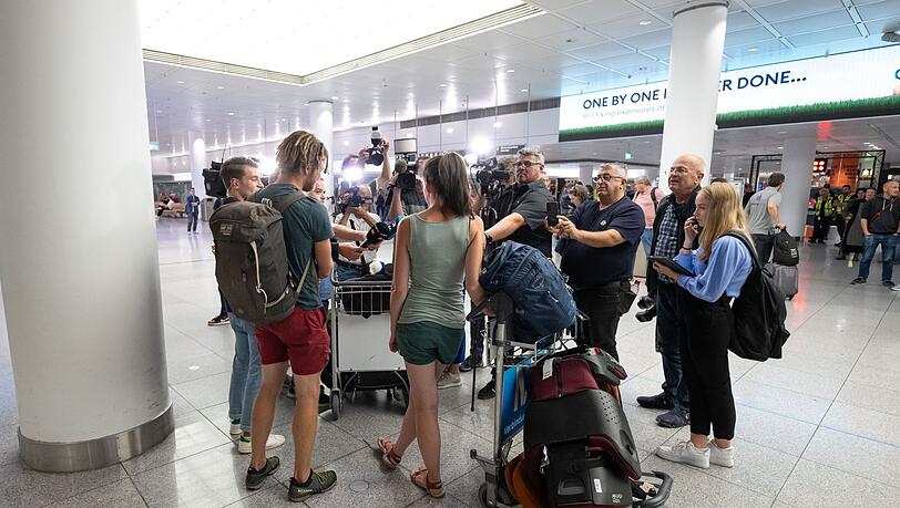 Die Touristen Franziska (M) und Alex Hanicke (2.v.r) sprechen mit den Medien, nachdem sie am Flughafen München ankamen.