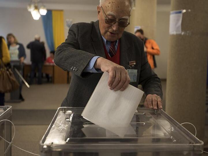 Ein Mann wirft in Kiew seinen Stimmzettel in eine Wahlurne.