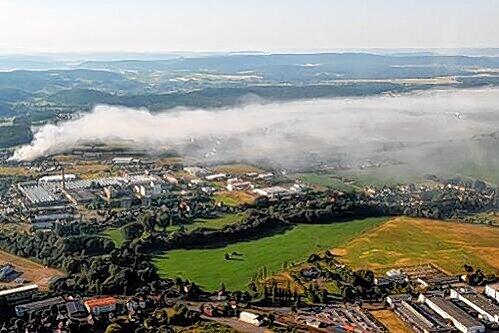 Dieses Luftbild zeigt das ganze Ausmaß der Qualmwolke, die von einer brennenden Lagerhalle in Föritz (links) im thüringischen Landkreis Sonneberg bis in die oberfränkische Nachbarstadt Neustadt bei Coburg zog.