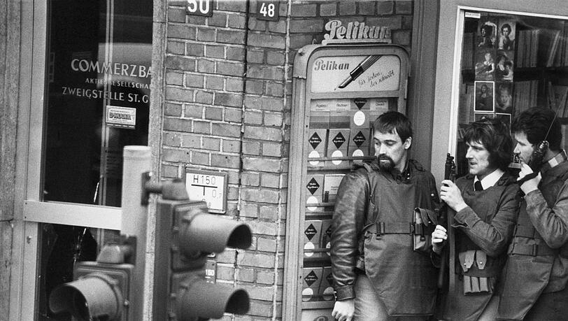 Am 18. April 1974 kommt es in der Commerzbank am Hamburger Steindamm zu einem Banküberfall mit anschließender Geiselnahme. Im Eingangsbereich des neben der Bank gelegenen Buch- und Schreibwarengeschäftes warten drei Angehörige des Mobilen Einsatzkommandos (MEK) mit Schutzwesten, Funkgerät, Pistole und Maschinenpistole auf ihren Einsatz. Am 18. April 1974 kommt es in der Commerzbank am Hamburger Steindamm zu einem Banküberfall mit anschließender Geiselnahme. Im Eingangsbereich des neben der Bank gelegenen Buch- und Schreibwarengeschäftes warten drei Angehörige des Mobilen Einsatzkommandos (MEK) mit Schutzwesten, Funkgerät, Pistole und Maschinenpistole auf ihren Einsatz.