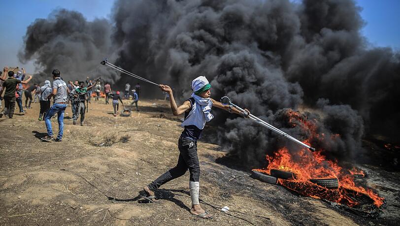 Ein Palästinenser schleudert Steine auf die israelische Armee bei Auseinandersetzungen an der Grenze zu Israel.