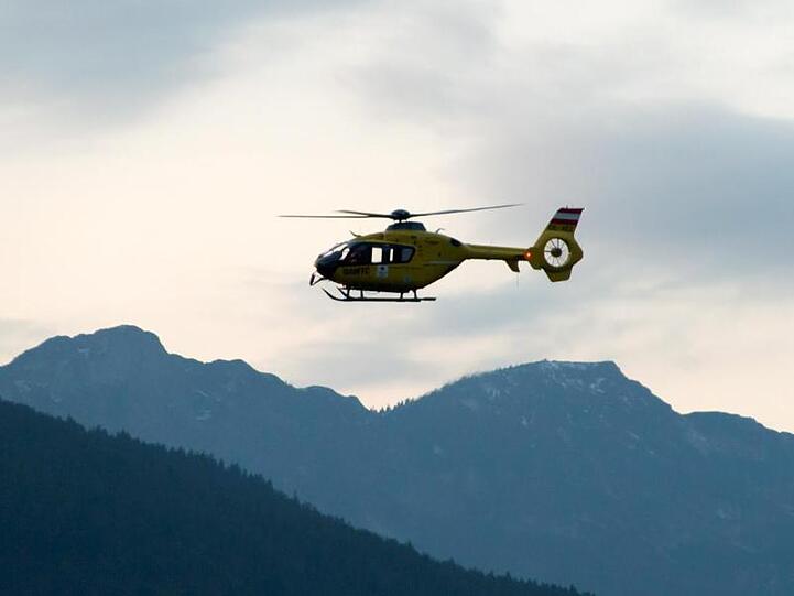 Ein Rettungshubschrauber fliegt über die Alpen. Foto: -/BRK BGL/dpa/Symbolbild