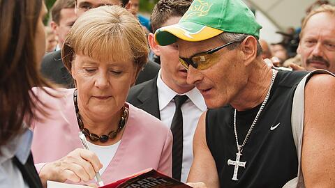 Aufpassen, wohin man seine Autogramme gibt: Merkel kritzelt beim Tag der Offenen Tür im Kanzleramt ausgerechnet in das Buch &bdquo;Der Staatsbankrott kommt&ldquo;.
