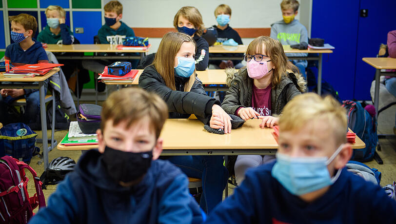 Schülerinnen und Schüler sitzen während des ersten Unterrichts nach den Herbstferien in ihrem Klassenzimmer und tragen dabei eine Alltagsmaske. Schülerinnen und Schüler sitzen während des ersten Unterrichts nach den Herbstferien in ihrem Klassenzimmer und tragen dabei eine Alltagsmaske.