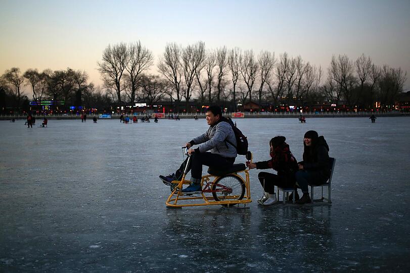 In China, hört man, ist es bitterkalt: ein Mann fährt mit einem Schlitten auf einem zugefrorenen See.