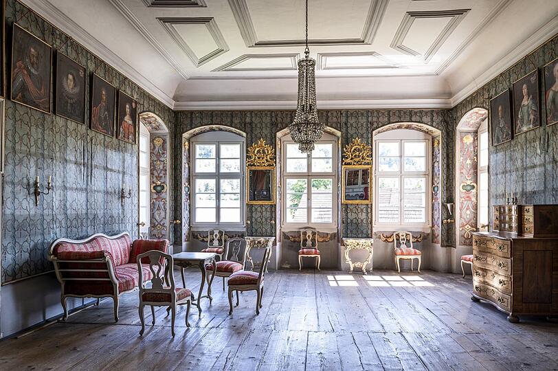 Der Salon des Schlosses mit Kronleuchter und Wandmalerei.