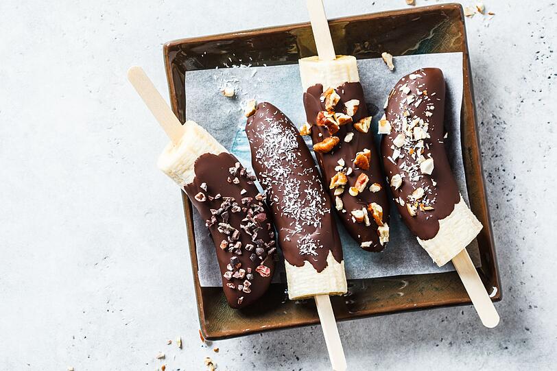 Bananen sind nicht nur eine leckere Zutat f&uuml;r Smoothie und Eiscreme. Denn die Schalenfr&uuml;chte lassen sich auch als Eis am Stiel verspeisen. Daf&uuml;r werden reife Bananen gesch&auml;lt, halbiert und auf einen Holzstab aufgespie&szlig;t. Danach kann das Bananen-Stieleis in fl&uuml;ssige Schokolade getunkt und mit gehackten N&uuml;ssen, Kokosflocken, Chiasamen oder Goji-Beeren garniert werden.