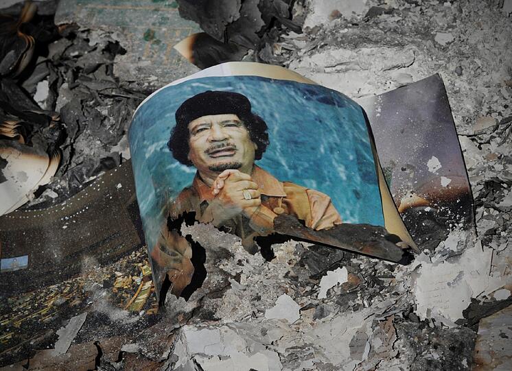 Ein angesengtes Foto von Muammar al Gaddafi liegt in den Trümmern seiner Heimatstadt Sirte. Hier wurde der Ex-Machthaber Libyens am Donnerstag gefasst.
