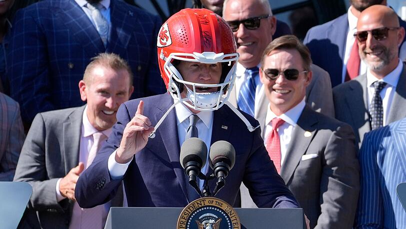 US-Präsident Joe Biden (M) trägt einen Helm von Super-Bowl-Champion Kansas City Chiefs bei einem Besuch im Weißen Haus.