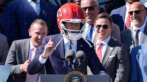 US-Präsident Joe Biden (M) trägt einen Helm von Super-Bowl-Champion Kansas City Chiefs bei einem Besuch im Weißen Haus.