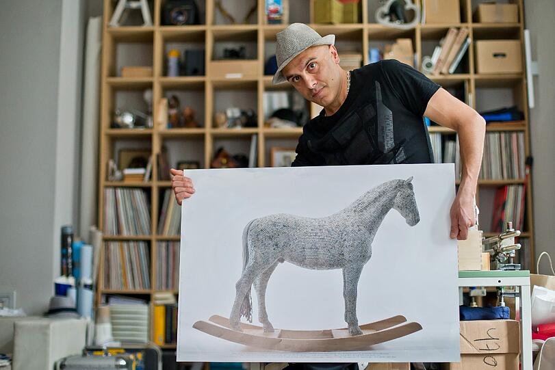 Der Künstler Babis Panagiotidis mit einem Poster seiner überlebensgroßen Pferde-Skulptur "Hedon is (my) Trojaner" in seinem Nürnberger Atelier.