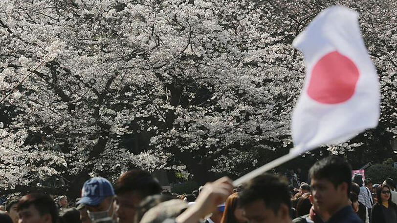 Eine japanische Flagge wird vor einem Kirschblütenbaum in Tokyo geschwenkt. Die Bevölkerung des Landes wird immer älter.