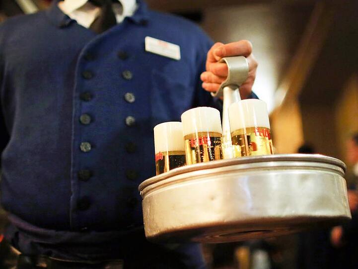 Ein Köbes (Kellner) serviert im Brauhaus Früh am Kölner Dom Kölsch-Bier.