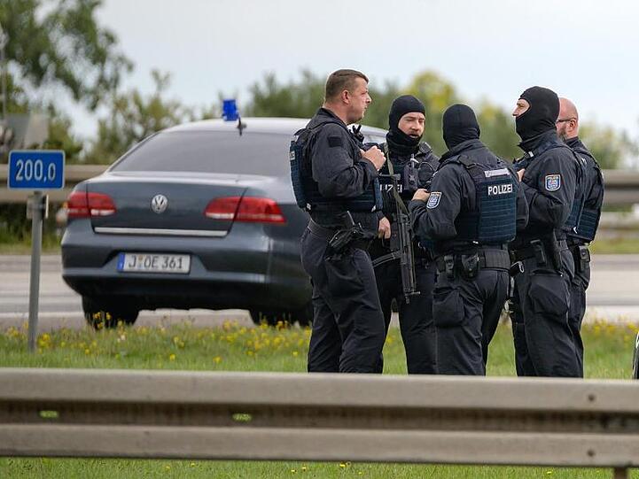 Bewaffnete Polizisten stehen mit zivilen Einsatzfahrzeugen an der Autobahnabfahrt Nohra.