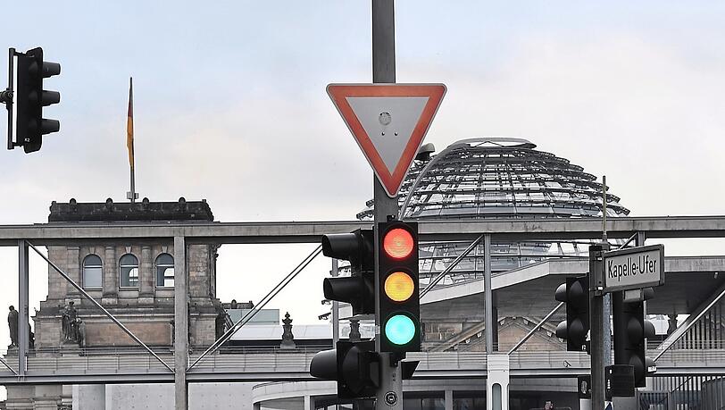 Eine Ampel, an der für einen Moment die Farben Rot, Gelb und Grün gleichzeitig leuchten. Hier berät der Bundestag final über den Haushaltsplan der Ampel-Koaltion. Für 2024 soll die Schuldenbremse aussetzen. Zwei der drei Parteien wollen jedoch eine Reform.