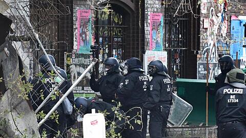 Polizisten räumen Barrikaden am Eingang der Bauwagensiedlung aus dem Weg.