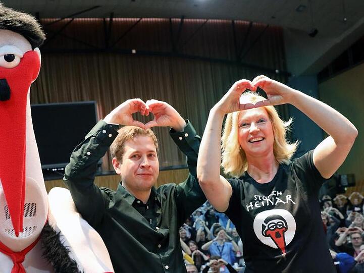Kevin Kühnert und Manuela Schwesig bilden das Symbol "Herz statt Hetze" zur Unterstützung der Proteste gegen ein Treffen des rechten Flügels der AfD in Binz, daneben Storch Heinar, eine Parodiefigur auf die Neonazi-Modemarke Thor Steinar.