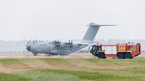 Ein Airbus-Militärtransporter A400M fährt an einem Einsatzfahrzeug der Flughafenfeuerwehr vorüber.