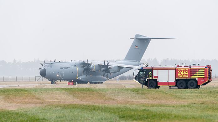 Ein Airbus-Militärtransporter A400M fährt an einem Einsatzfahrzeug der Flughafenfeuerwehr vorüber.