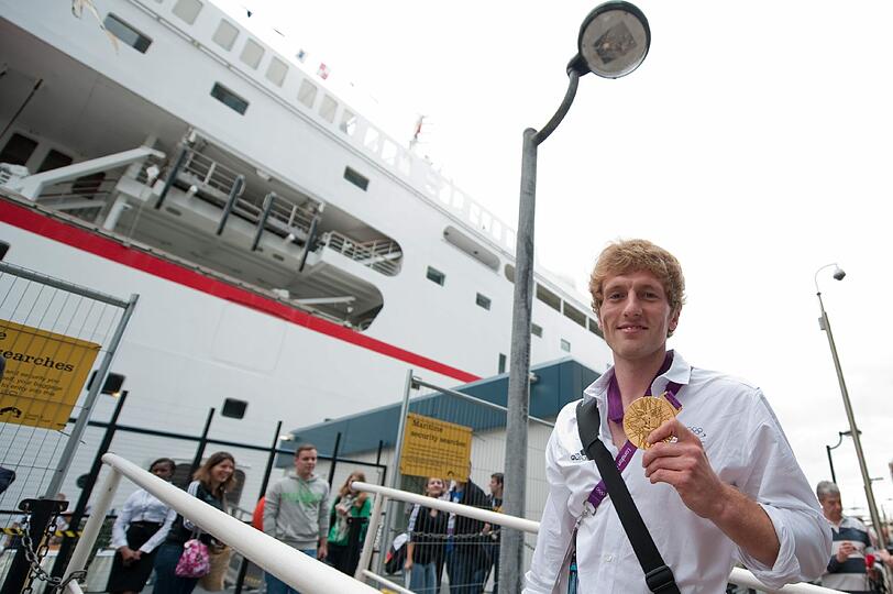 Der Hockeyspieler Jan Philipp Ranbante posiert waehrend des Boardings deutscher Athleten vor dem Kreuzfahrschiff MS Deutschland mit seiner Goldmedaille.