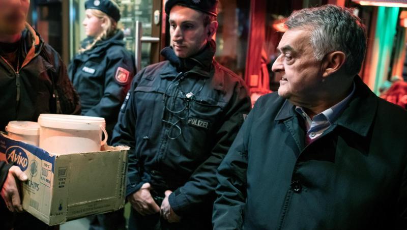 Herbert Reul (r), Innenminister von Nordrhein-Westfalen, verfolgt, wie nach einer Razzia Beweismittel aus einer Shisha-Bar getragen werden.