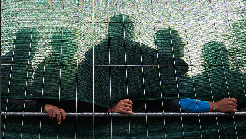 Flüchtlinge stehen hinter einem Zaun einer Asylunterkunft in Hamburg (Symbolbild). Flüchtlinge stehen hinter einem Zaun einer Asylunterkunft in Hamburg (Symbolbild).