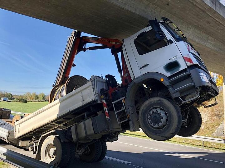 Ein Lkw bleibt mit seinem Ladekran an einer Brücke hängen.