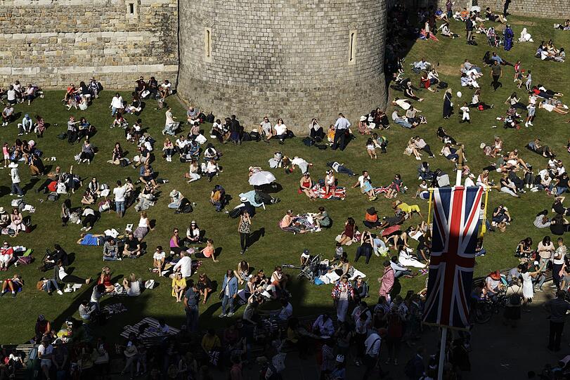 Nach der Hochzeit sonnen sich die Zuschauer auf dem Gras vor Windsor Castle.