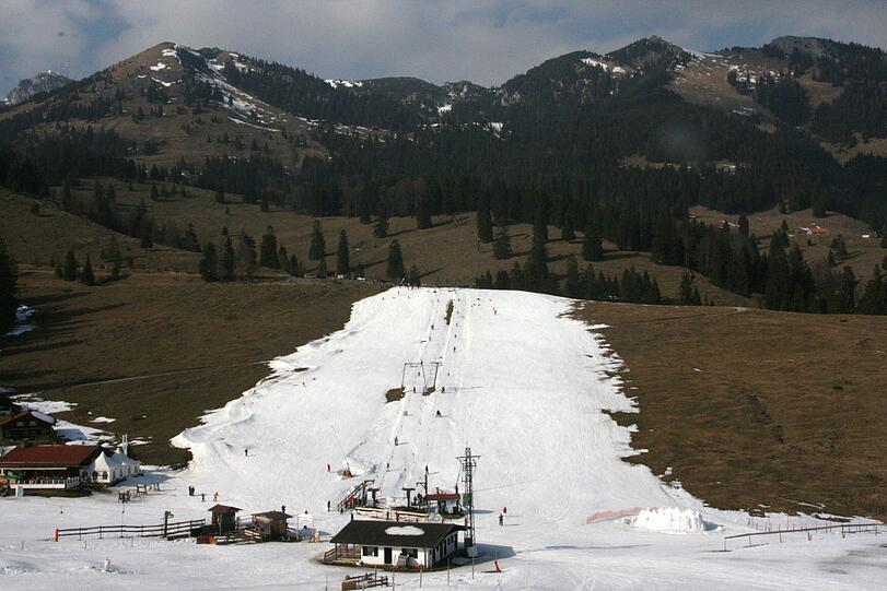 Ohne Kunstschnee geht am Sudelfeld (fast) nichts: Eine weiße Piste inmitten grüner Wiesen.