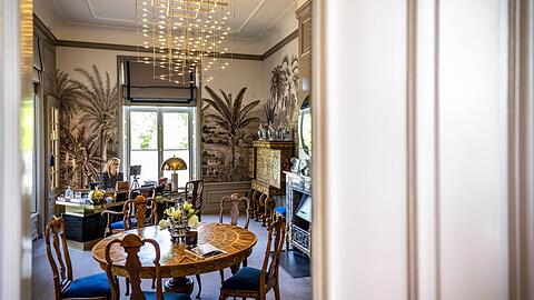 Schöner arbeiten: Königin Máxima im stilvollen Arbeitszimmer &ndash; Palmentapete, Hingucker-Lampe und Goldapfel auf dem Schreibtisch.