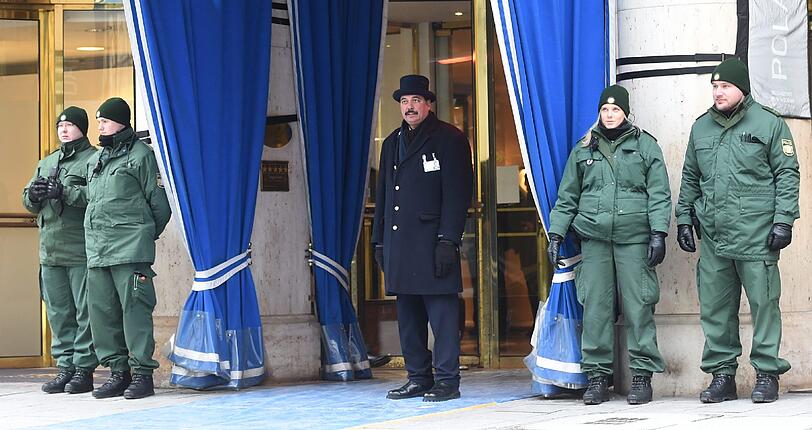 Warm eingepackt sichern Polizisten den Haupteingang zum Bayerischen Hof, dem Tagungshotel. Der Portier hält nach den ersten Gästen Ausschau.