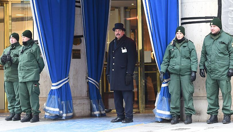 Warm eingepackt sichern Polizisten den Haupteingang zum Bayerischen Hof, dem Tagungshotel. Der Portier hält nach den ersten Gästen Ausschau.