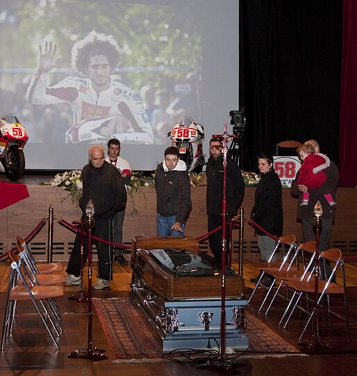 Der Sarg Simoncellis wurde heute in einem Theather von Rimini aufgebahrt. Das Foto im Hintergrund wirkt wie ein letzter Gruß.