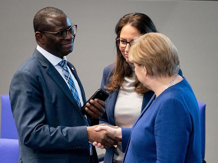 Bundeskanzlerin Angela Merkel (CDU) stellt sich hinter den SPD-Bundestagsabgeordneten Karamba Diaby (li), nachdem dessen Bürgerbüro angegriffen wurde.