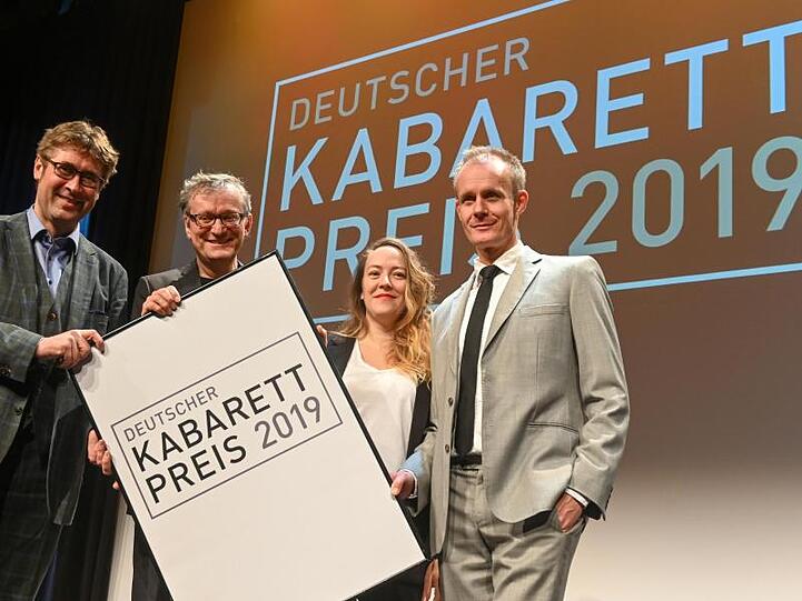 Detlef Simon (Desimo, l-r), Sonderpreis-Gewinner, Moderator Frank Lüdecke, Lisa Catena, Förderpreis-Gewinnerin, und Preisträger Max Uthoff stehen bei der Verleihung des Deutschen Kabarett-Preises auf der Bühne. Foto: Berny Meyer/dpa/Archivbild