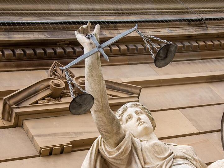 Vor einem Gericht hält eine Statue der Justitia eine Waage in der Hand. Foto: Stefan Puchner/dpa/Archivbild