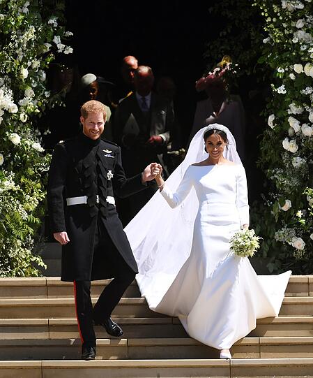 Herzogin Meghan wird von ihrem frisch angetrauten Ehemann Prinz Harry aus der St.-Georg's-Kapelle geleitet. Zum schlichten Brautkleid mit Carmen-Ausschnitt trägt Meghan einen langen Schleier.