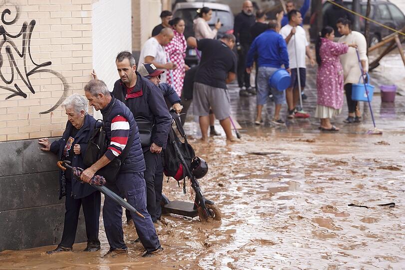 Menschen in Valencia gehen durch überflutete Straßen.