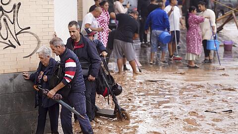 Menschen in Valencia gehen durch überflutete Straßen.