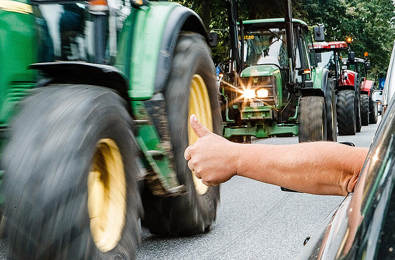 Ein Autofahrer begrüßt mit hochgerecktem Daumen in Hohenwestedt (Schleswig-Holstein) Milchbauern, die mit ihren Fahrzeugen zu einer bundesweiten Staffelfahrt nach München aufbrechen.