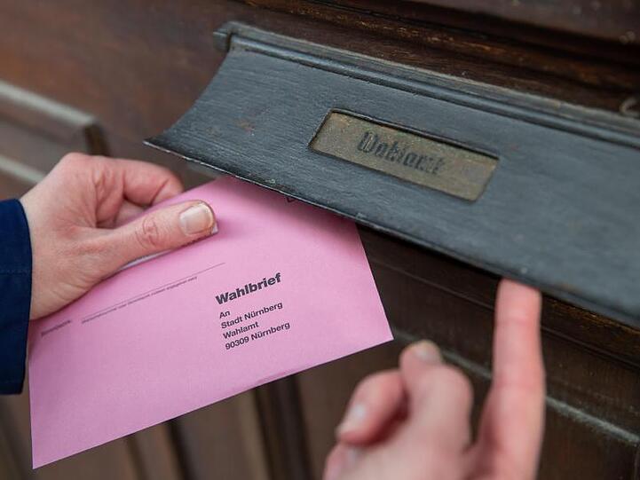 Eine Frau wirft Briefwahlunterlagen in den Briefkasten eines Wahlamtes. Foto: Daniel Karmann/dpa/Illustration