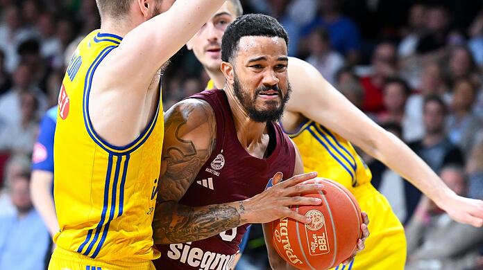 Nick Weiler-Babb (M) von München und Malte Delow (l) von Berlin kämpfen um den Ball.
